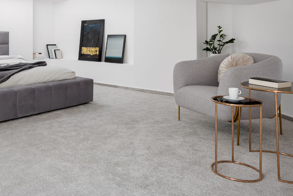 A stylish bedroom with a grey bed and chair, emphasizing carpet tile flooring services in Renton, WA.